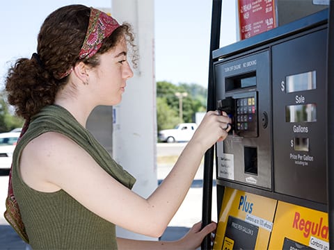 A woman using her credit car to purchase gas at a pump